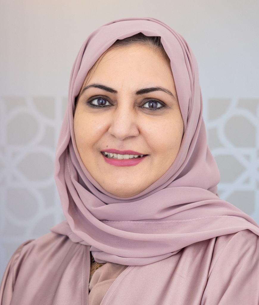 Fatma R., Teacher, smiling in a dusty pink hijab and matching abaya