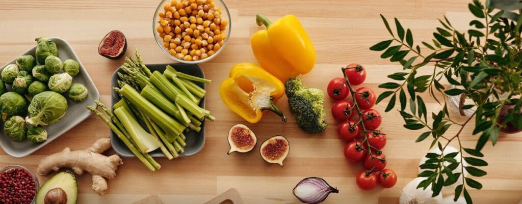 Fresh vegetables, herbs, figs and chickpeas laid out on a wooden board