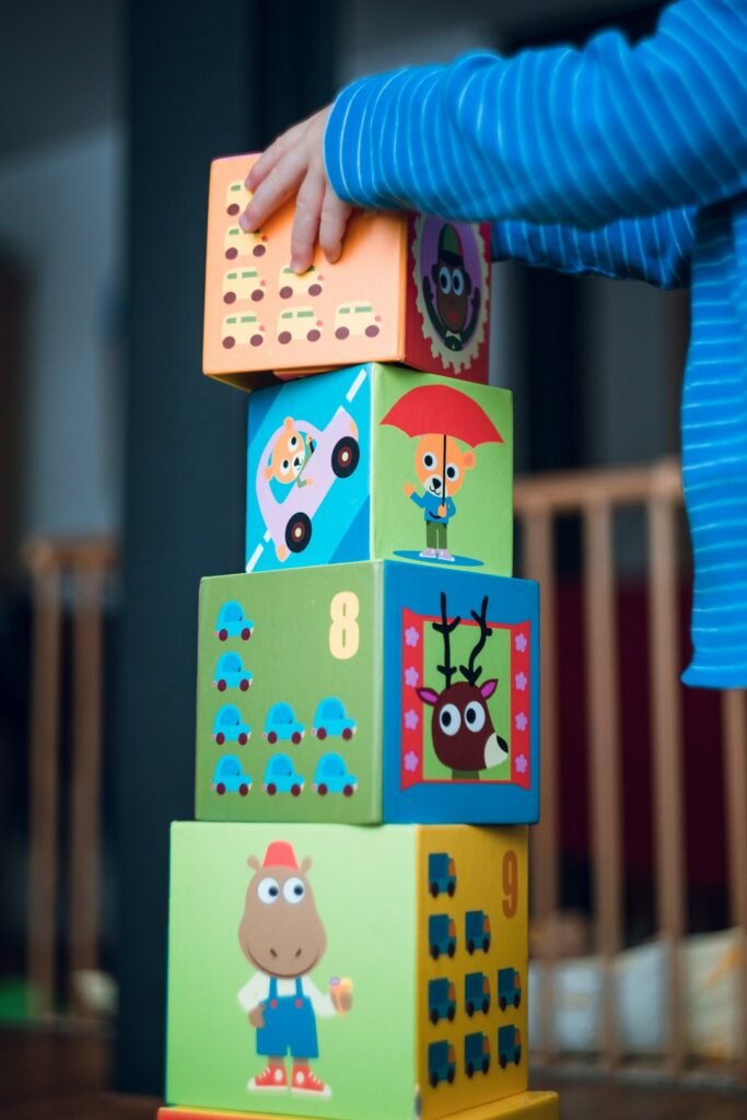 Child's hand stacking colourful toy blocks into a tower