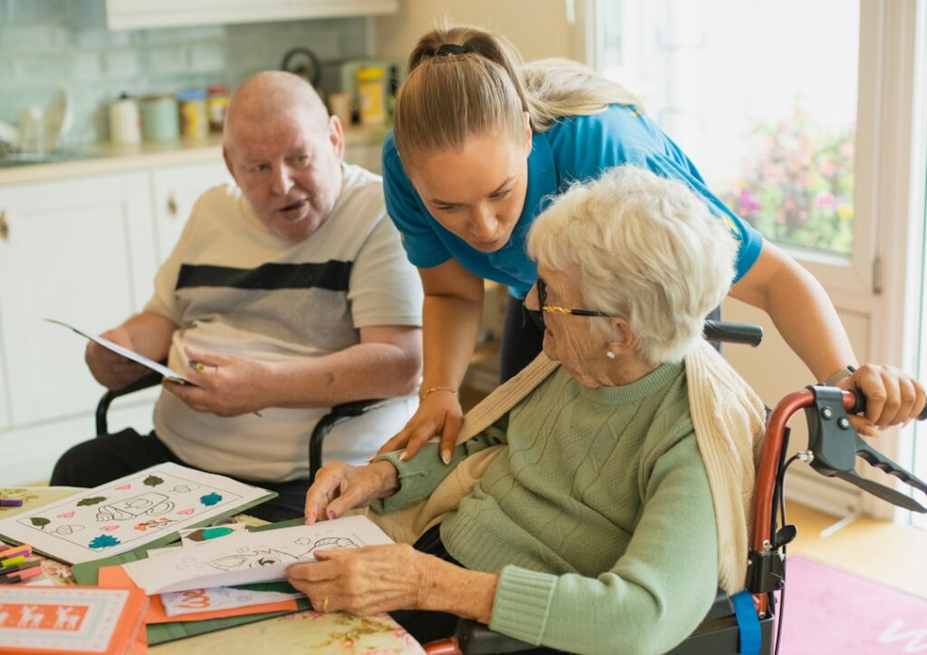 Carer helping two older people with a puzzle activity at a table