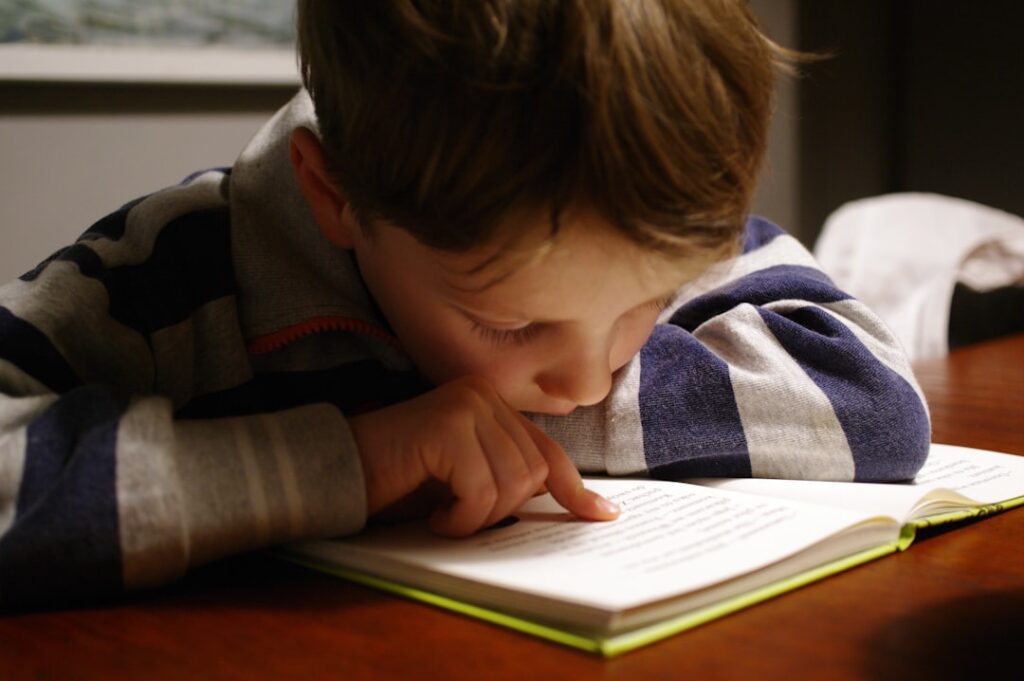 Boy reading a book, following the line with his finger